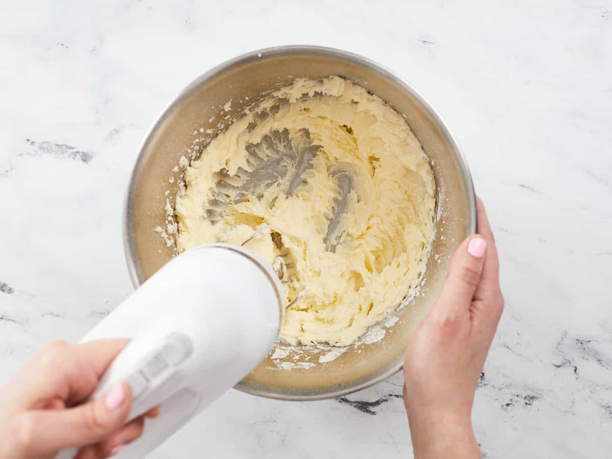 Overhead shot of sugar being mixed into softened butter.