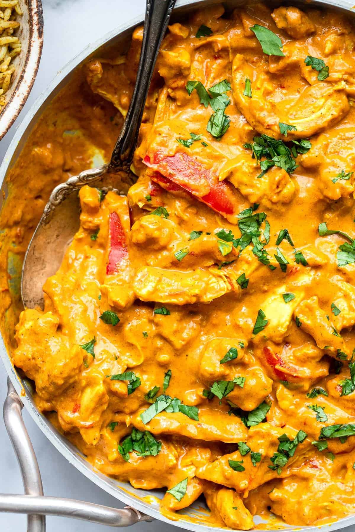 close up photo of paleo chicken curry in a serving bowl with cilantro on top