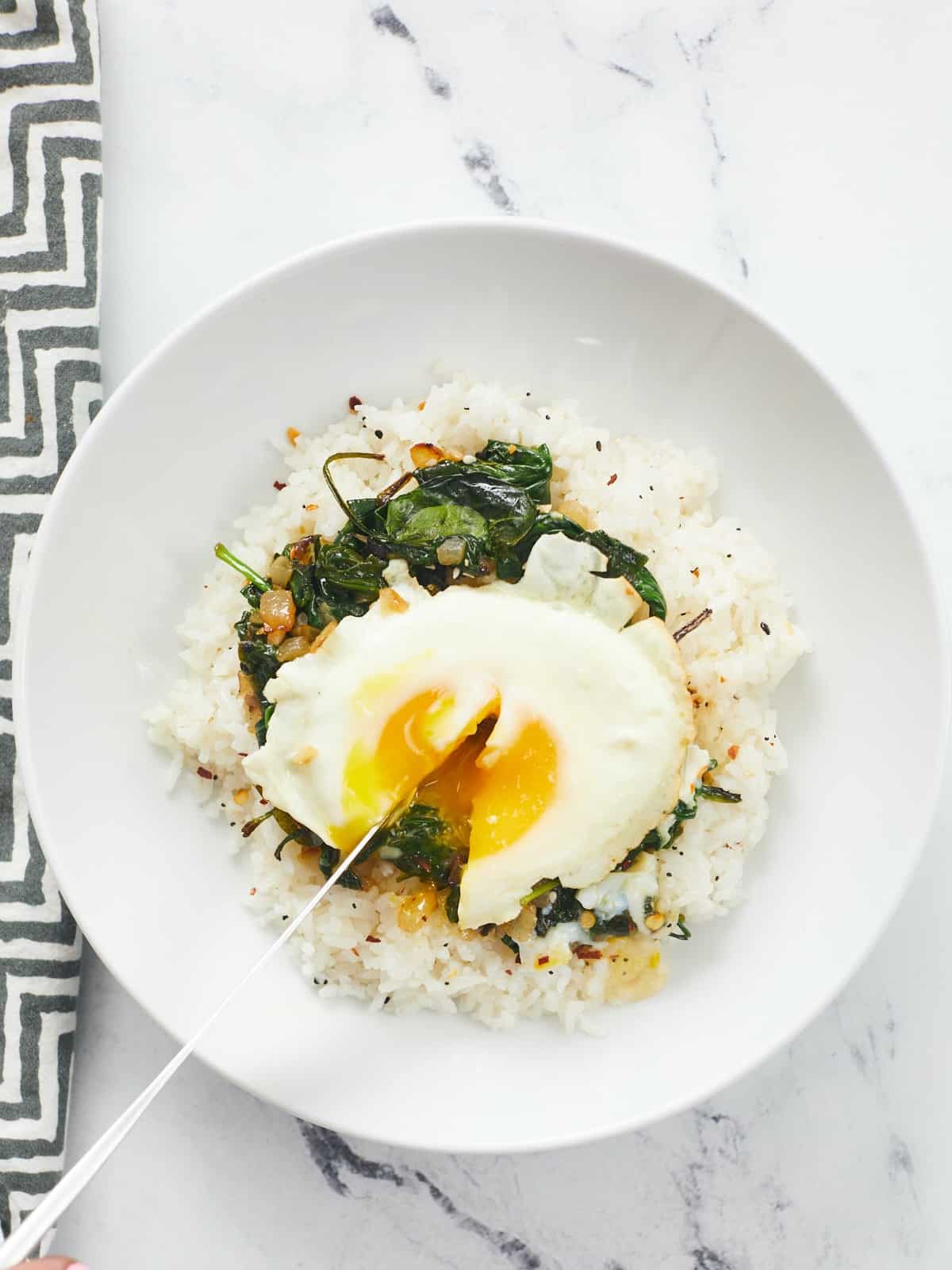 Overhead shot of Everything Bagel Rice Bowl with a knife cutting into the egg.