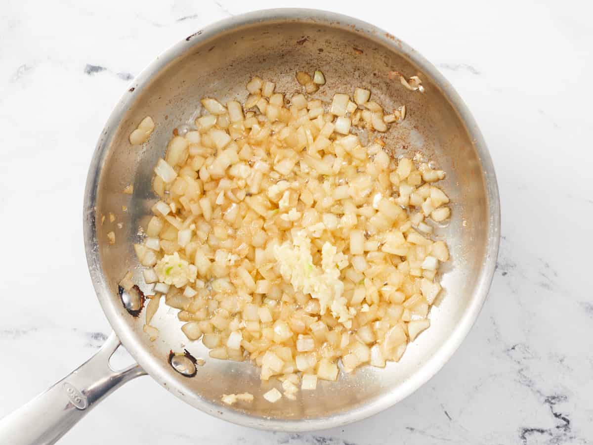 Overhead shot of onions and garlic cooking in a pot.