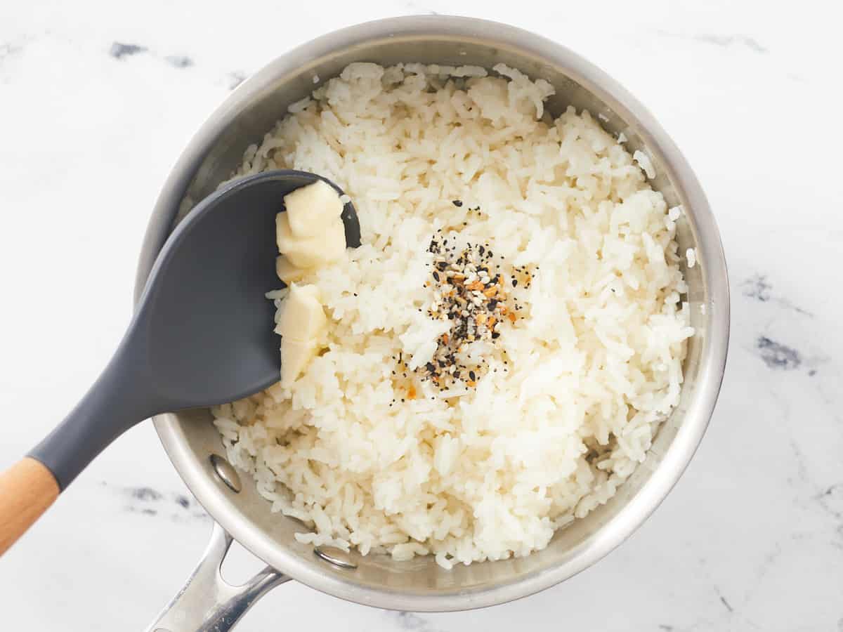 Overhead shot of Everything Bagel seasoning and butter being added to rice.