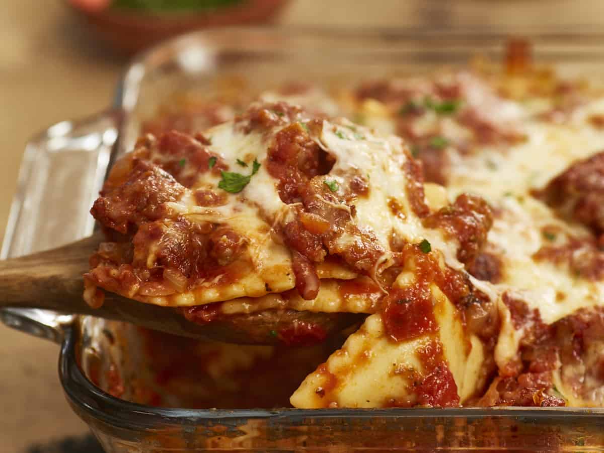 Side shot of baked ravioli being scooped out of the dish.