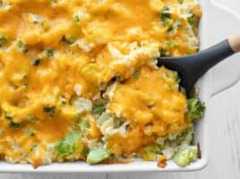 Broccoli cheddar casserole being scooped out of the dish