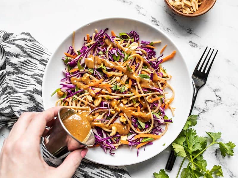 Peanut Lime Dressing being poured onto a bowl of Cold Peanut Noodle Salad