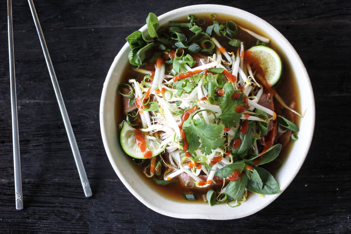 Easy Beef Pho Recipe in a white bowl with stainless steel chopsticks.