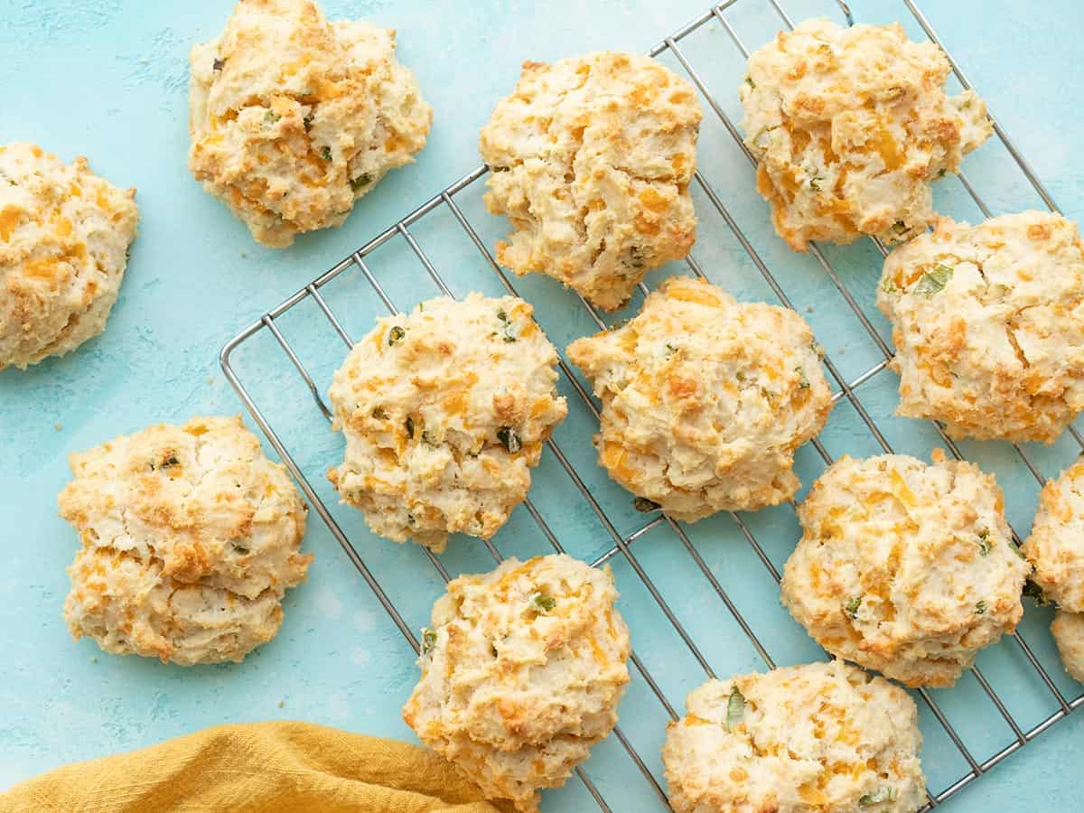 Cheddar drop biscuits on a wire cooling rack against a blue background