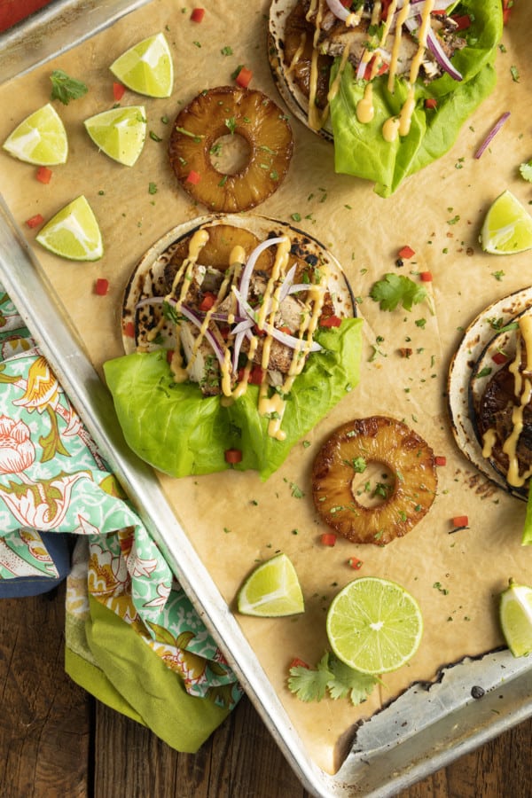 Make taco nights magical with jerk chicken tacos! Fresh lettuce leaves stacked on charred tortillas are piled high with juicy jerk chicken, grilled pineapple slices, diced bell peppers, thinly sliced onions, a drizzle of sauce or spoonful of mango salsa.