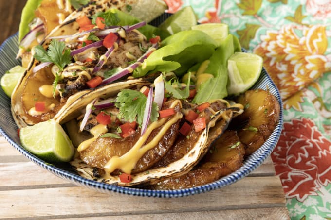 Make taco nights magical with jerk chicken tacos! Fresh lettuce leaves stacked on charred tortillas are piled high with juicy jerk chicken, grilled pineapple slices, diced bell peppers, thinly sliced onions, a drizzle of sauce or spoonful of mango salsa.