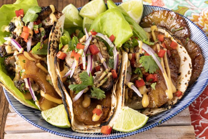 Make taco nights magical with jerk chicken tacos! Fresh lettuce leaves stacked on charred tortillas are piled high with juicy jerk chicken, grilled pineapple slices, diced bell peppers, thinly sliced onions, a drizzle of sauce or spoonful of mango salsa.