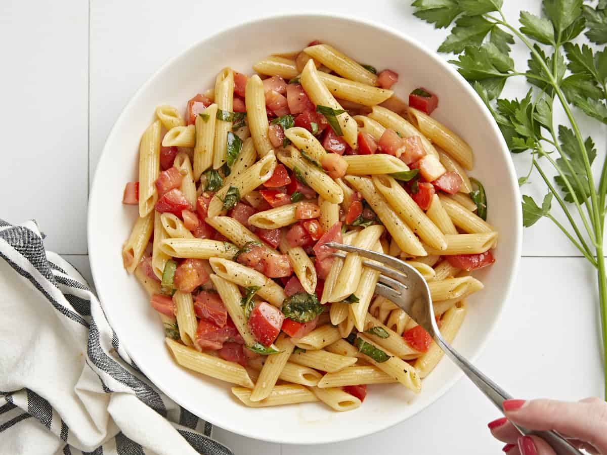 Overhead view of bruschetta pasta in a bowl with a fork.