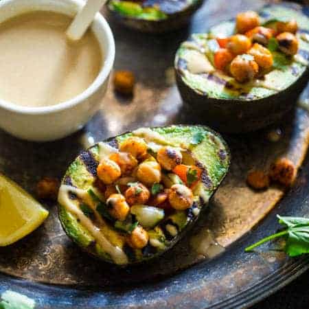 Vegan Mediterranean Chickpea Stuffed Grilled Avocado - Grilled avocado is stuffed with fresh cucumber, tomato and crispy grilled chickpeas! A drizzle of tahini makes this a delicious, healthy and easy, vegan dinner for under 250 calories! | Foodfaithfitness.com | @FoodFaithFit