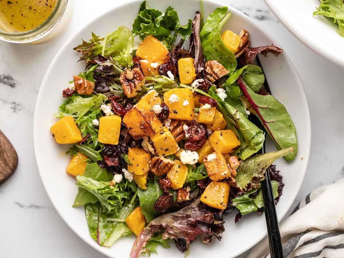 Close up overhead shot of one serving of butternut squash salad in a bowl.