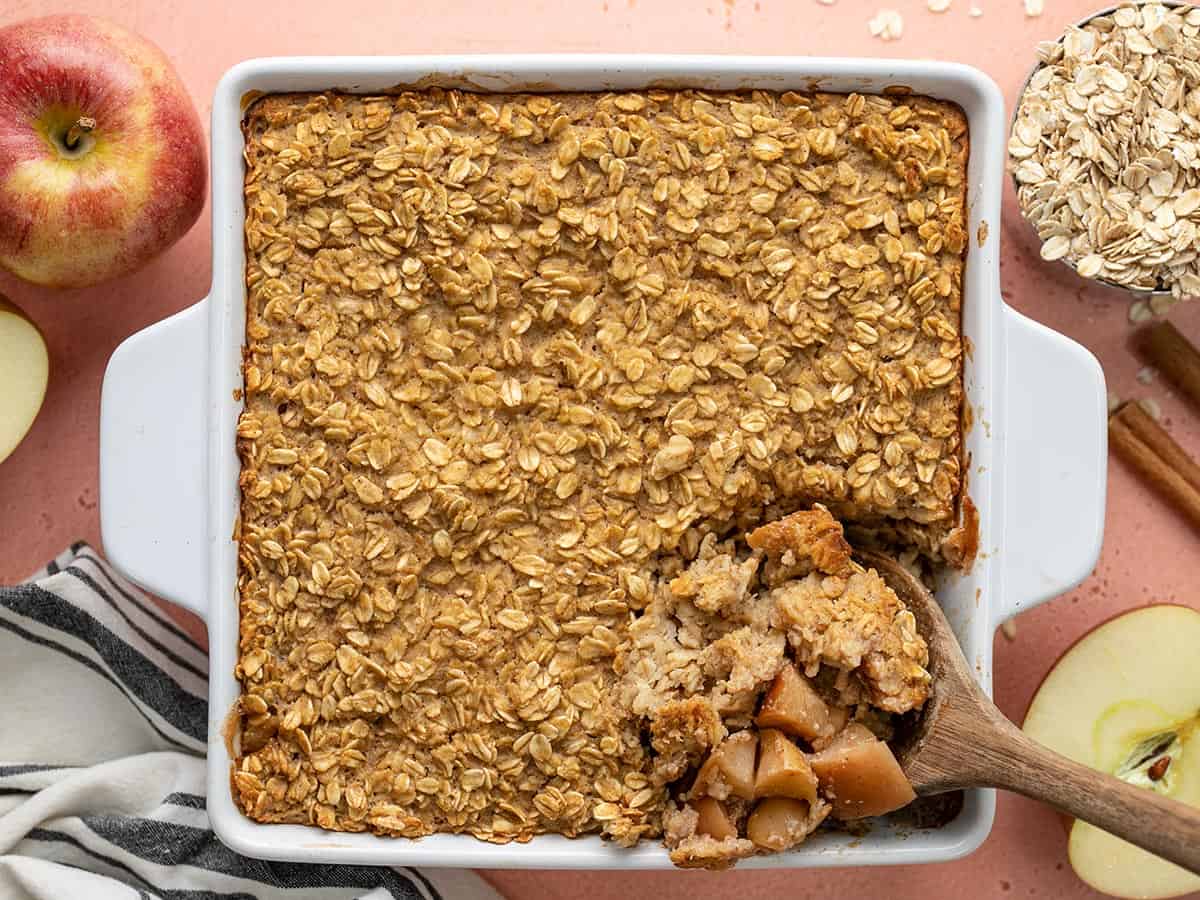 Overhead view of a casserole dish of apple cinnamon baked oatmeal with the corner being scooped out.