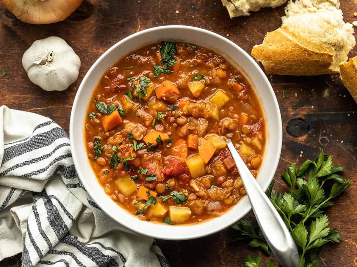 A bowl of tomato lentil sup with bread on the side