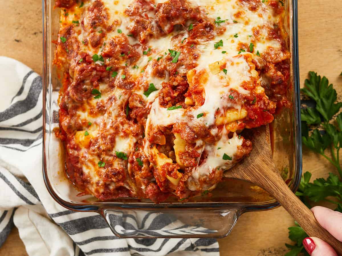 Baked ravioli being scooped out of the baking dish.