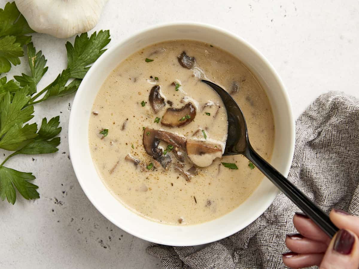 Overhead view of a bowl of creamy mushroom soup with a spoon in the center.