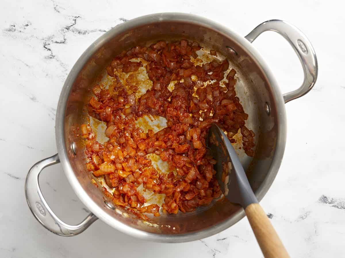 Tomato paste stirred into the onions and garlic in the saucepot.