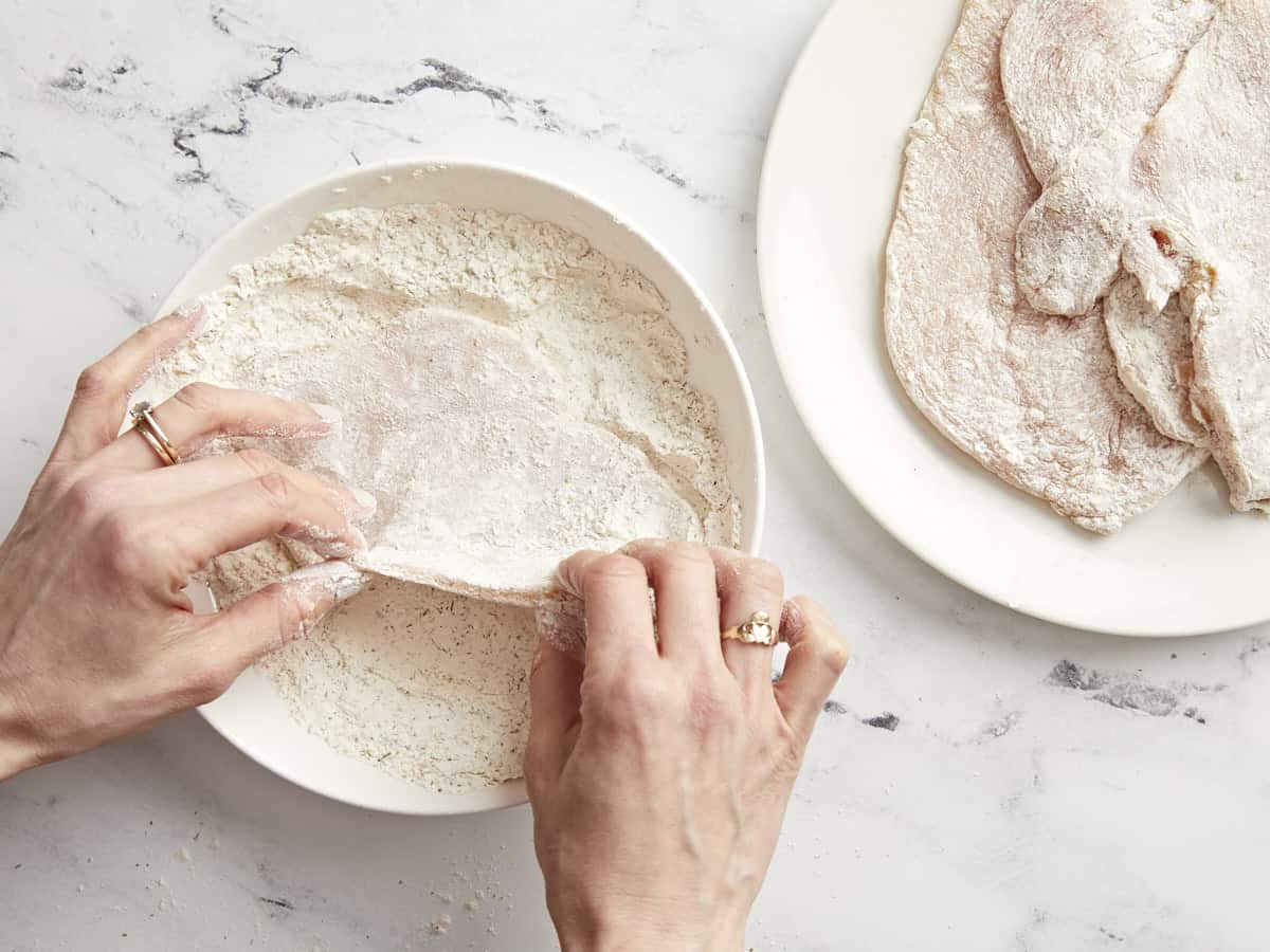 dredging chicken breasts in seasoned flour.